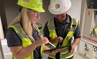 Female construction intern with mentor looking at ipad