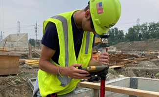 Construction intern surveying at jobsite