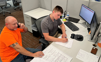Construction intern at office setting with coach working